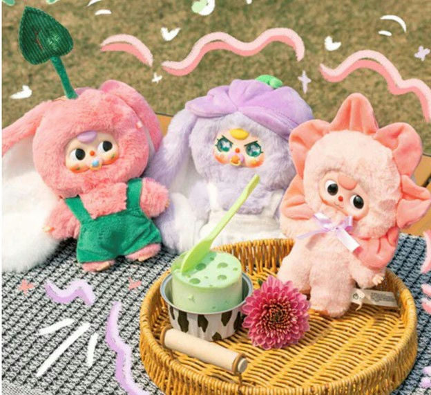 Three plush toys with pastel colors on a textured surface with decorative elements.