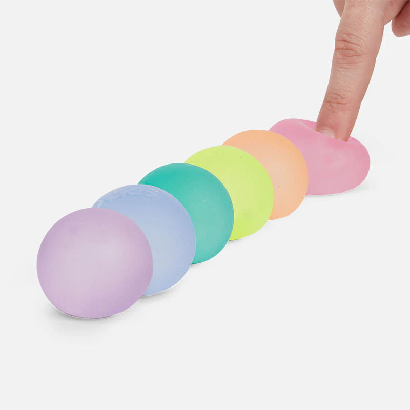 Pastel-colored stress balls arranged in a row with a hand reaching out to touch one.