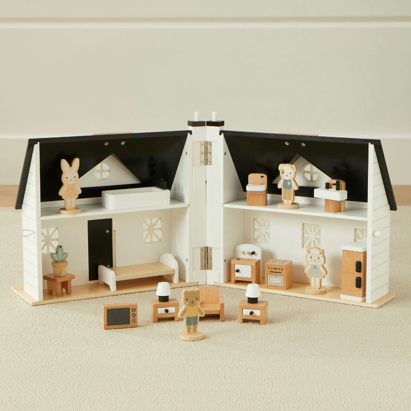 Wooden toy house with miniature furniture and figures on a neutral background