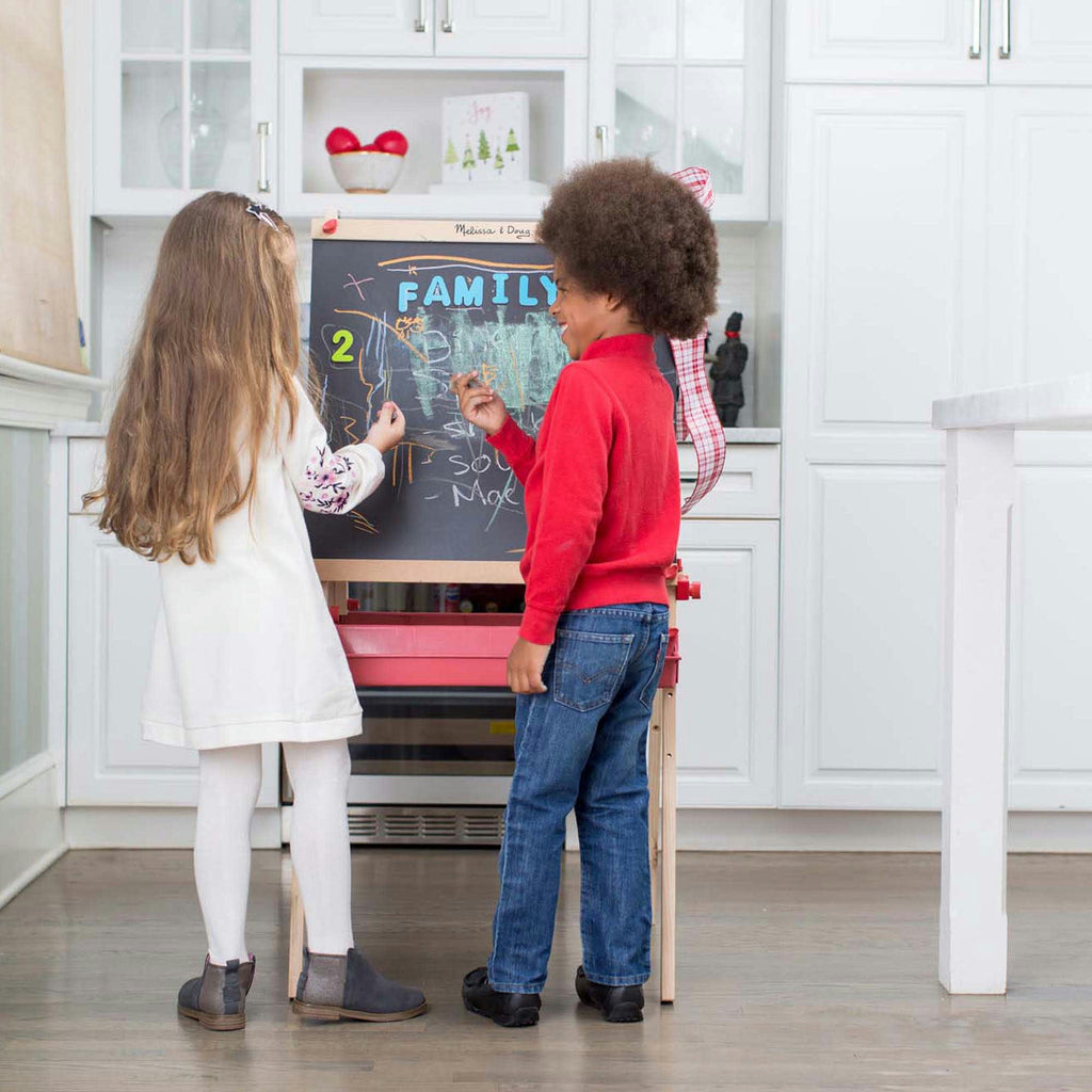 Two children interacting with a blackboard in a kitchen setting