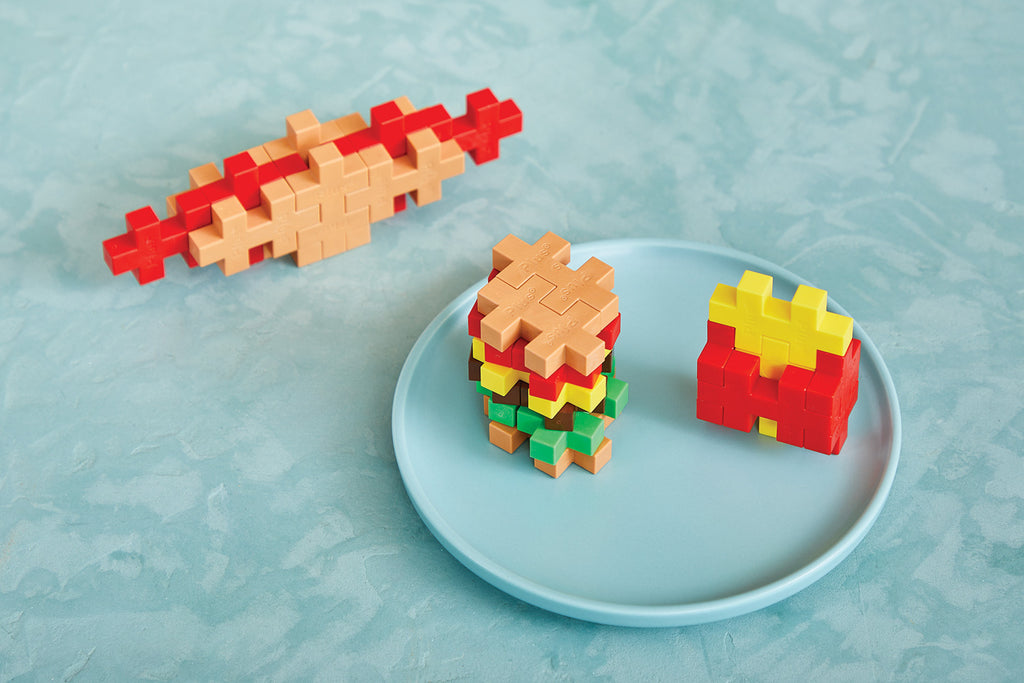 Colorful toy building blocks on a blue plate against a light blue background