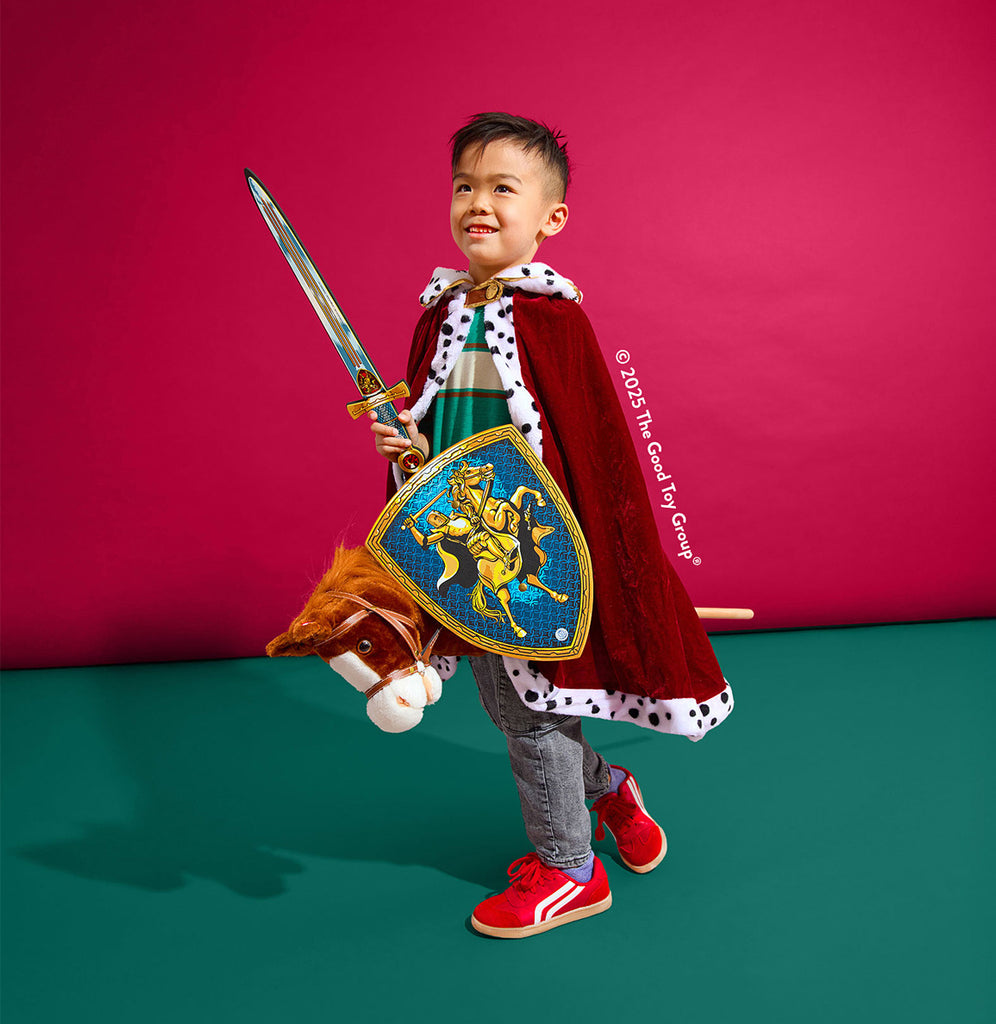 Child in a knight costume holding a sword and shield against a red background