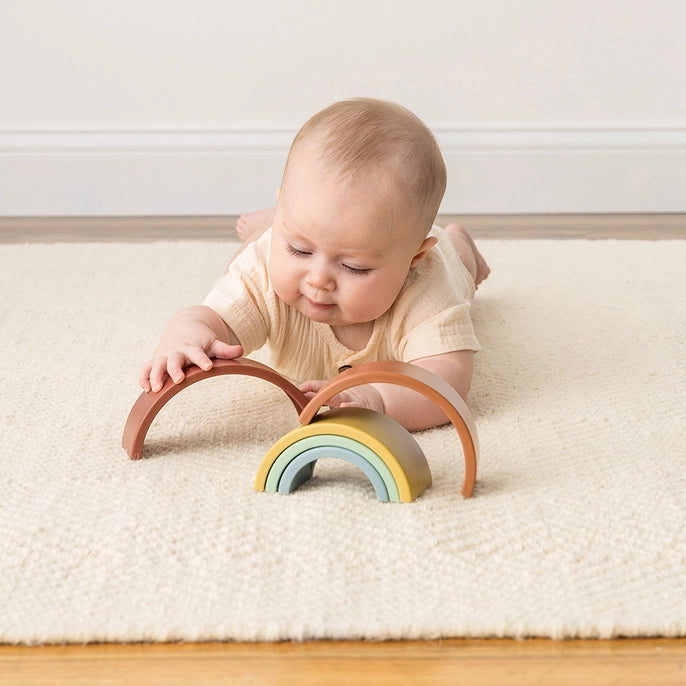 Image of child playing with Itzy Ritzy stacking toy on the floor