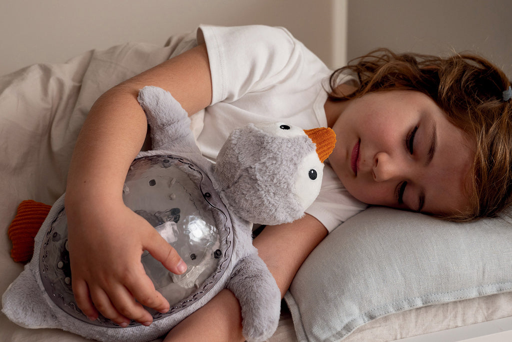 Child sleeping with a plush toy resembling a penguin
