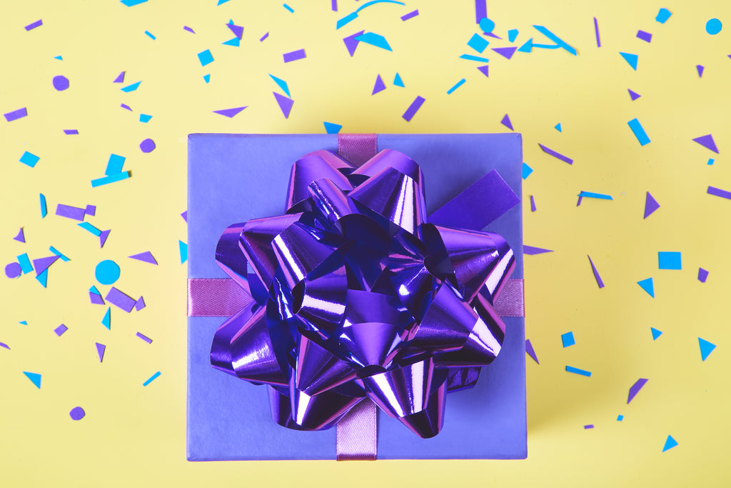 Image of gift with purple bow and confetti